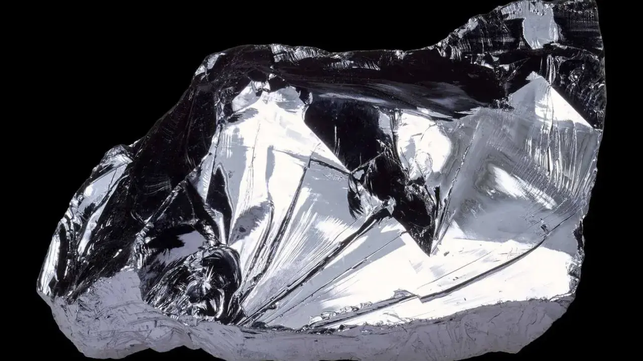 Frammento lucido di silicio puro, metallico, con sfaccettature che riflettono la luce. Il suo elevato punto di fusione lo rende fondamentale nell'elettronica.