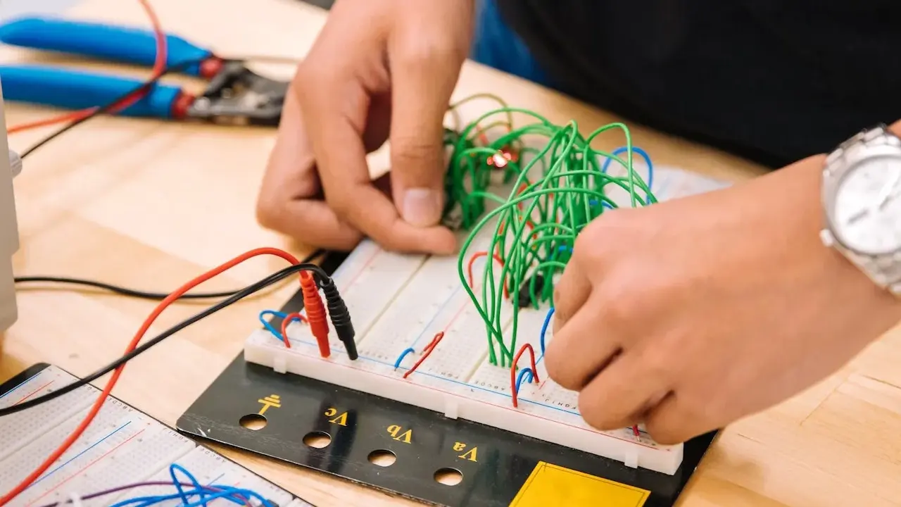 Mani che assemblano circuiti su breadboard, un'attività che fa riflettere su quanto guadagna un meccanico industriale.