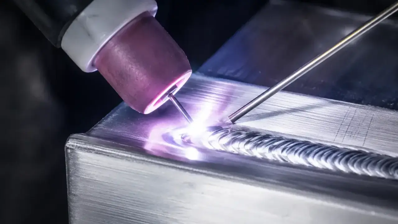Saldatura magnesio con torcia TIG, creando un cordone preciso e luminoso su un pezzo metallico.