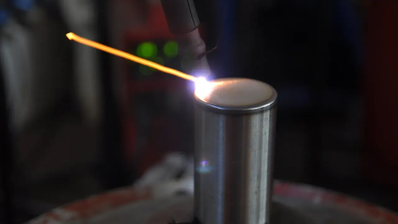 Un arco di saldatura GTAW illumina un cilindro metallico. La precisione del processo crea un cordone perfetto.