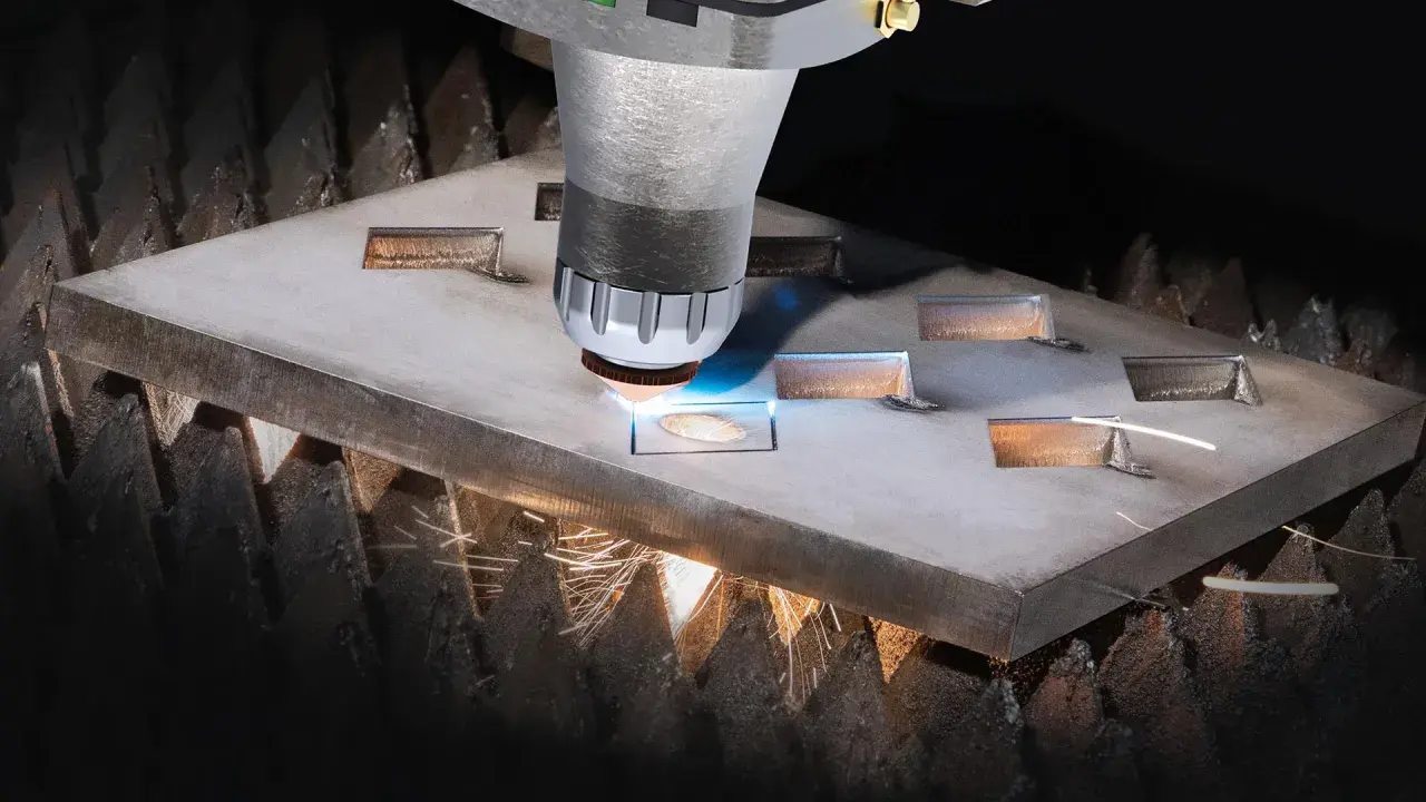 Macchina da taglio laser che crea forme precise su una lastra metallica. Il fascio luminoso e le scintille mostrano il **taglio termico**, un processo industriale avanzato.