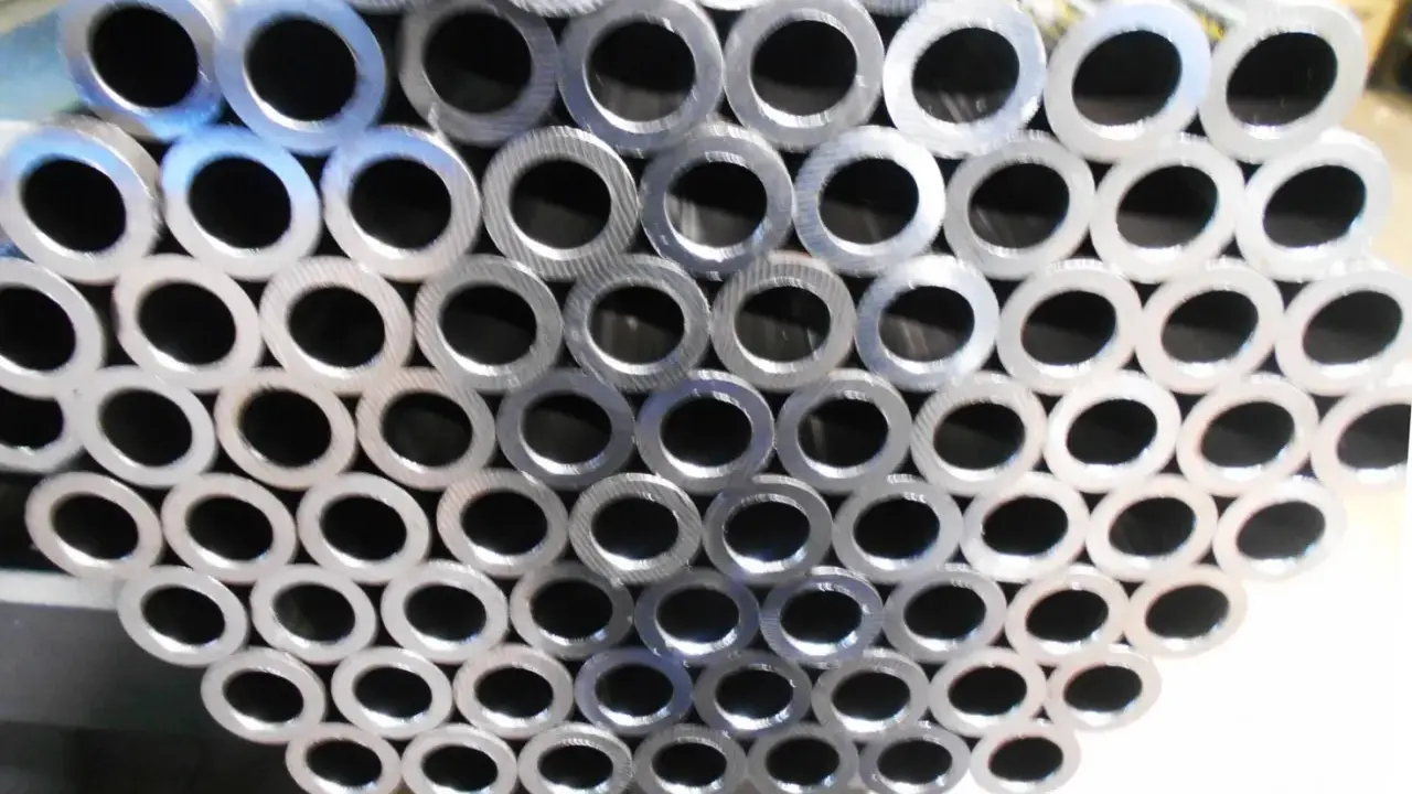 Un mucchio di tubi in acciaio al carbonio, con la sigla visibile su alcuni di essi, pronti per essere utilizzati.
