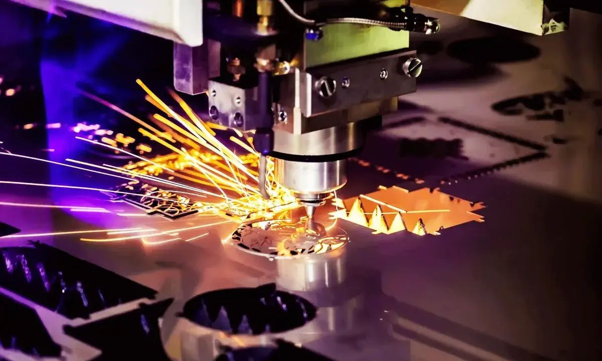 Macchina per **taglio laser** in azione, con scintille dorate che volano mentre crea forme precise su un foglio di metallo.