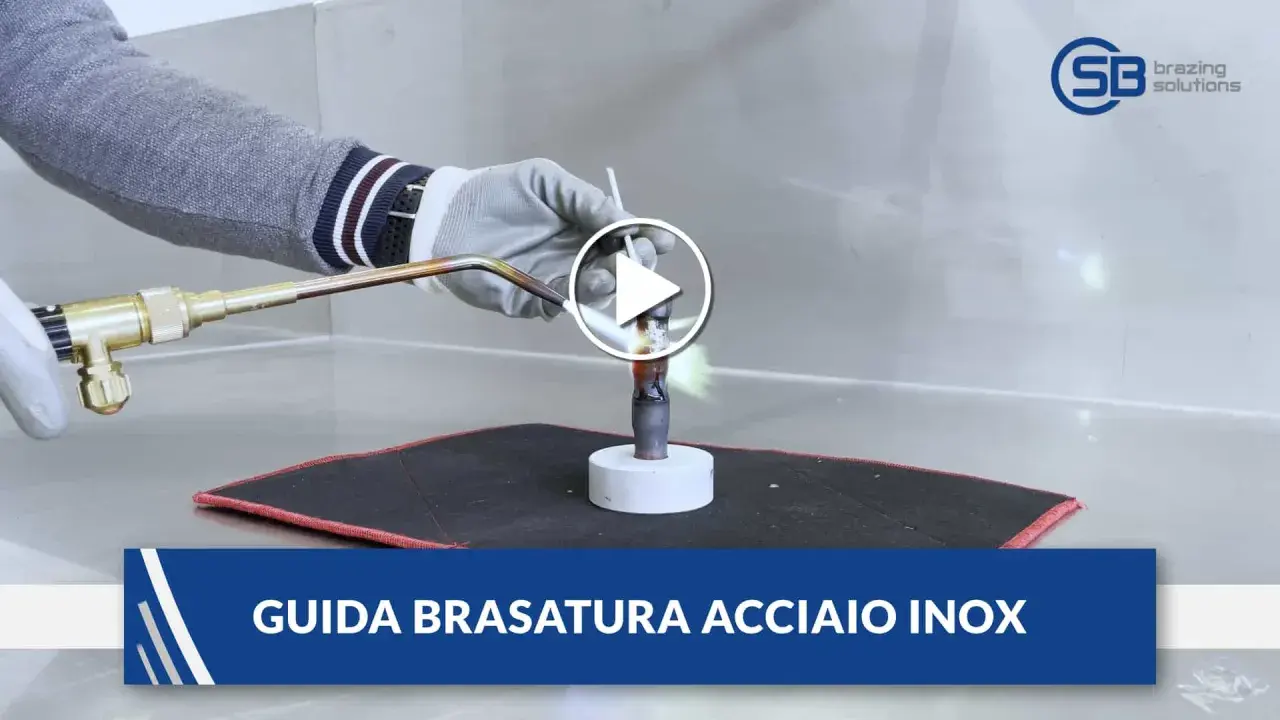Guida alla brasatura ferro: un operatore con guanti usa una torcia per riscaldare un tubo metallico, mostrando la fiamma viva.