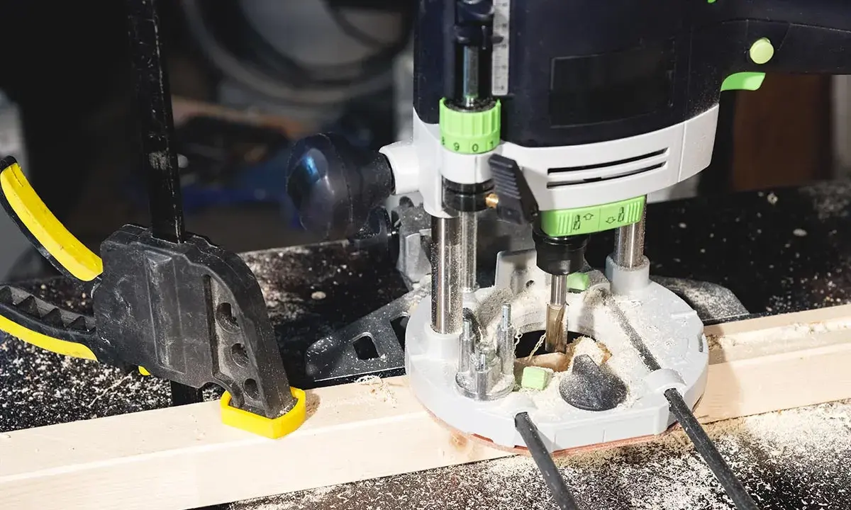 Fresatrice verticale in azione su un pezzo di legno, fissato con morsetto. Guida pratica su come usare fresatrice verticale per lavori precisi.