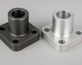 Due flange quadrate, una scura in cromo molibdeno e una chiara in alluminio, su sfondo grigio.