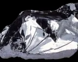Frammento lucido di silicio puro, metallico, con sfaccettature che riflettono la luce. Il suo elevato punto di fusione lo rende fondamentale nell'elettronica.