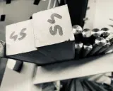 Blocchi di metallo con numeri "45" e "55" scritti sopra, pronti per essere lavorati. Accanto, barre di acciaio inossidabile aisi 309 lucide.