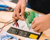Mani che assemblano circuiti su breadboard, un'attività che fa riflettere su quanto guadagna un meccanico industriale.