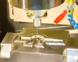 Fresatrice CNC in azione, che lavora un pezzo metallico complesso. Il corso CAD è fondamentale per creare questi dettagli precisi.