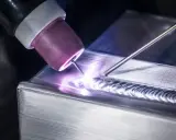 Saldatura magnesio con torcia TIG, creando un cordone preciso e luminoso su un pezzo metallico.