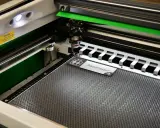 Macchina per taglio laser in azione, che realizza un cartello "Ascenseur" con simboli per bagni. Perfetta per progetti di taglio laser personalizzati.