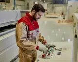Un tornitore CNC esperto opera un pannello di controllo in una moderna officina, concentrato sul suo lavoro.
