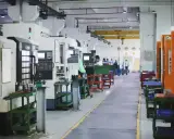 Fabbrica moderna con macchine utensili all'avanguardia, dove operai qualificati creano componenti di precisione.