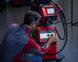 Operatore regola i parametri di saldatura su una macchina Fronius, ottimizzando l'apporto termico per un lavoro preciso.