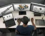 Un disegnatore CAD freelance lavora su un sistema a triplo monitor, creando modelli 3D e disegni tecnici.