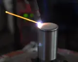 Un arco di saldatura GTAW illumina un cilindro metallico. La precisione del processo crea un cordone perfetto.