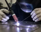 Saldatura GMAW: un saldatore con maschera e guanti crea un cordone di saldatura brillante su metallo.