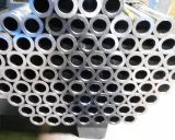 Un mucchio di tubi in acciaio al carbonio, con la sigla visibile su alcuni di essi, pronti per essere utilizzati.