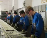 Giovani apprendisti in officina, concentrati sul loro lavoro. L'operatore meccanico cosa fa? Impara a usare strumenti e macchinari per creare e riparare componenti.
