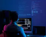 Programmatore con cuffie lavora al suo computer, analizzando dati e codice su più schermi. Il cam software illumina la stanza con luci blu e rosa.