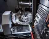 Macchinario CNC in azione, con un casco da ciclista in lavorazione. La manutenzione macchinari industriali è fondamentale per precisione e efficienza.