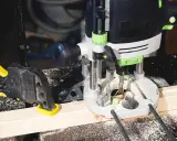 Fresatrice verticale in azione su un pezzo di legno, fissato con morsetto. Guida pratica su come usare fresatrice verticale per lavori precisi.