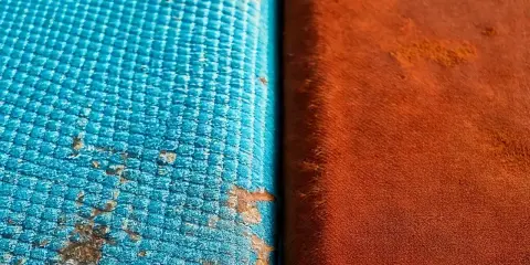 Dettaglio di un test di **salt spray** su due materiali: uno blu con macchie di corrosione, l'altro arancione.
