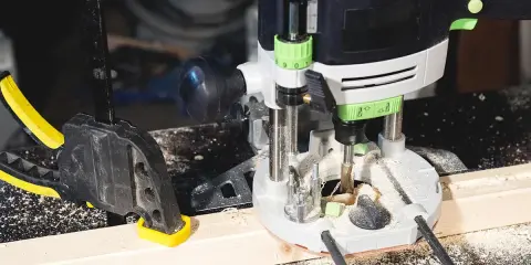 Fresatrice verticale in azione su un pezzo di legno, fissato con morsetto. Guida pratica su come usare fresatrice verticale per lavori precisi.