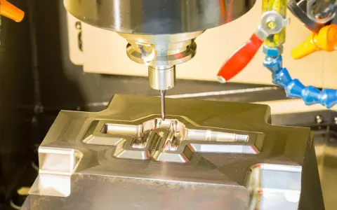 Fresatrice CNC in azione, che lavora un pezzo metallico complesso. Il corso CAD è fondamentale per creare questi dettagli precisi.