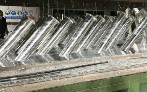 Tubi metallici immersi in un bagno, pronti per la zincatura. La lega di zinco conferirà loro resistenza alla corrosione.