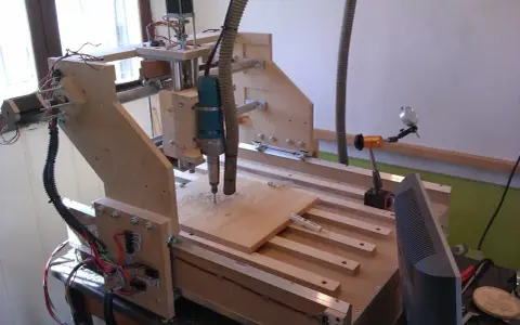 Macchina **cnc fai da te** in legno, con fresa in azione su un pannello.