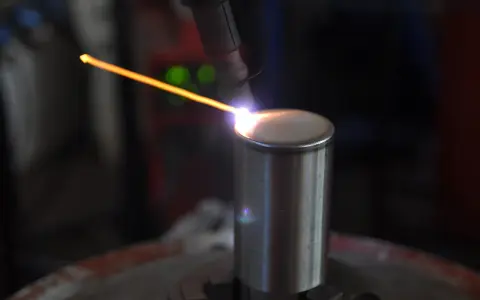 Un arco di saldatura GTAW illumina un cilindro metallico. La precisione del processo crea un cordone perfetto.
