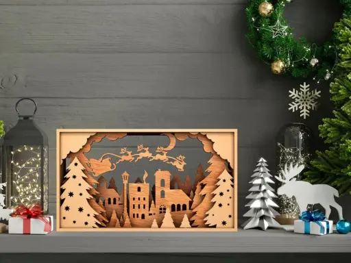 Scena natalizia con Babbo Natale e renne in volo, creata con disegni taglio laser su legno. Un villaggio innevato e alberi completano il quadro.