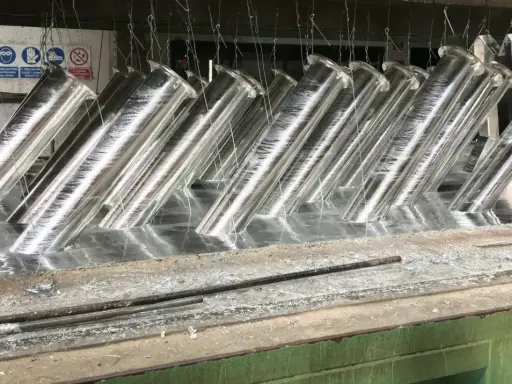 Tubi metallici immersi in un bagno, pronti per la zincatura. La lega di zinco conferirà loro resistenza alla corrosione.