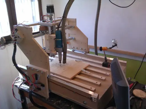 Macchina **cnc fai da te** in legno, con fresa in azione su un pannello.
