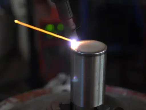 Un arco di saldatura GTAW illumina un cilindro metallico. La precisione del processo crea un cordone perfetto.