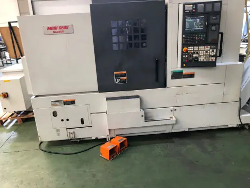 Tornio Mori Seiki NL2500 in officina, con pannello di controllo e pedali arancioni.