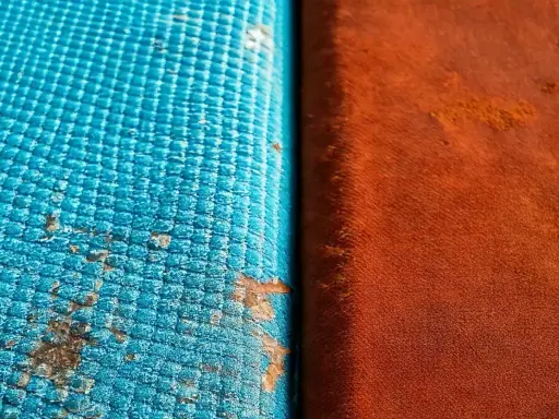 Dettaglio di un test di **salt spray** su due materiali: uno blu con macchie di corrosione, l'altro arancione.
