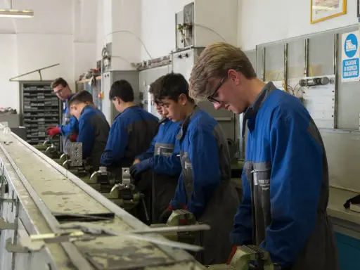 Giovani apprendisti in officina, concentrati sul loro lavoro. L'operatore meccanico cosa fa? Impara a usare strumenti e macchinari per creare e riparare componenti.