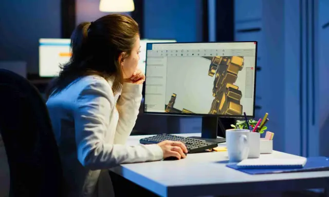 Operatore CAD lavora di notte su un progetto complesso, concentrato sul modello 3D visualizzato sullo schermo.