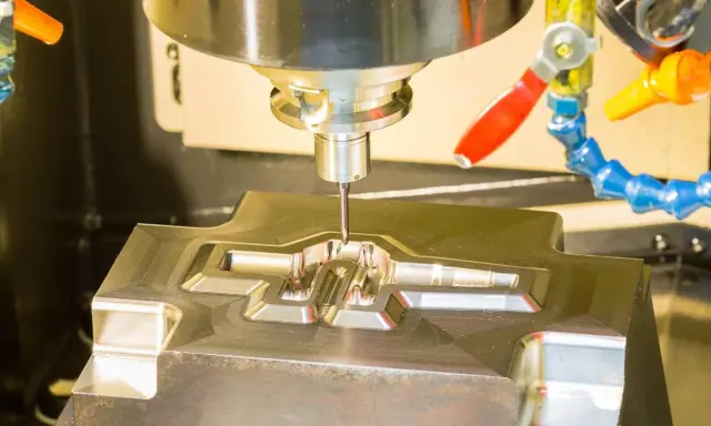Fresatrice CNC in azione, che lavora un pezzo metallico complesso. Il corso CAD è fondamentale per creare questi dettagli precisi.