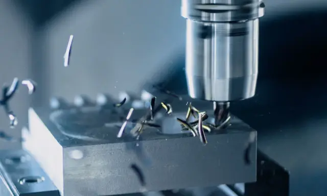 Fresatura di metallo con utensile rotante. Trucioli metallici volano via mentre la programmazione ISO guida la lavorazione di precisione.