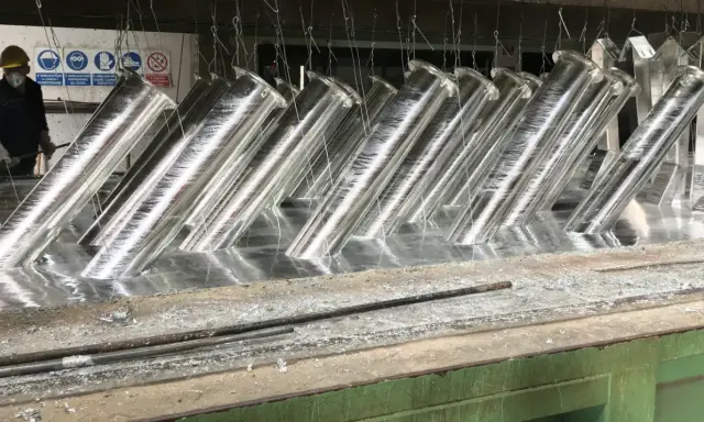 Tubi metallici immersi in un bagno, pronti per la zincatura. La lega di zinco conferirà loro resistenza alla corrosione.