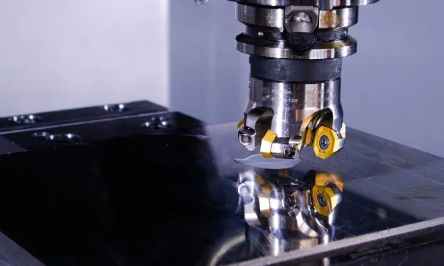 Testa di fresatura su una lastra metallica lucida, riflesso della precisione di un operatore CNC.