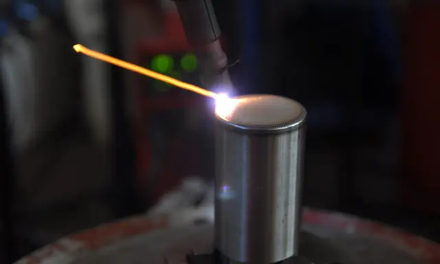 Un arco di saldatura GTAW illumina un cilindro metallico. La precisione del processo crea un cordone perfetto.