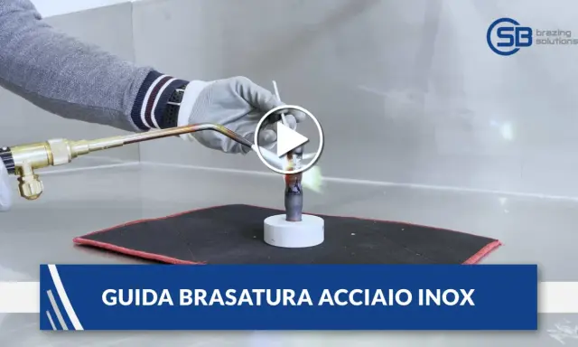 Guida alla brasatura ferro: un operatore con guanti usa una torcia per riscaldare un tubo metallico, mostrando la fiamma viva.