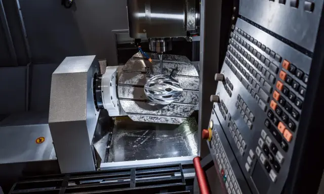 Macchinario CNC in azione, con un casco da ciclista in lavorazione. La manutenzione macchinari industriali è fondamentale per precisione e efficienza.