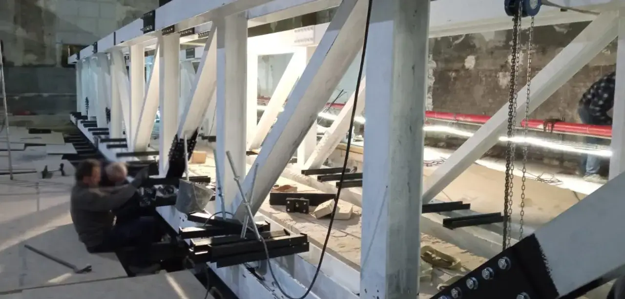 Operai al lavoro su una struttura in acciaio, con saldatura in corso per rinforzare i collegamenti.