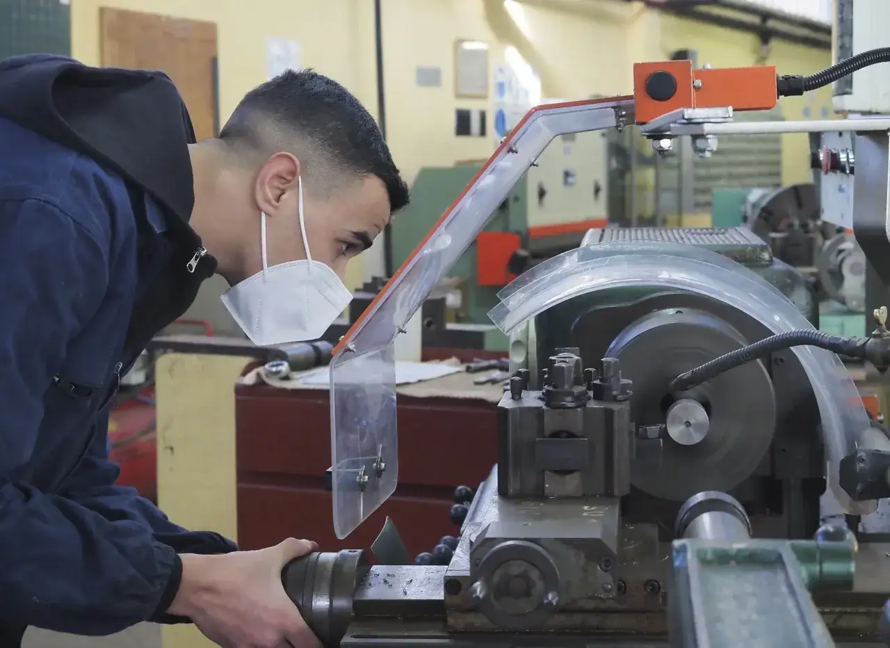 Giovane attrezzista meccanico al lavoro su un tornio. Un mestiere che richiede precisione, con uno stipendio che riflette l'esperienza.